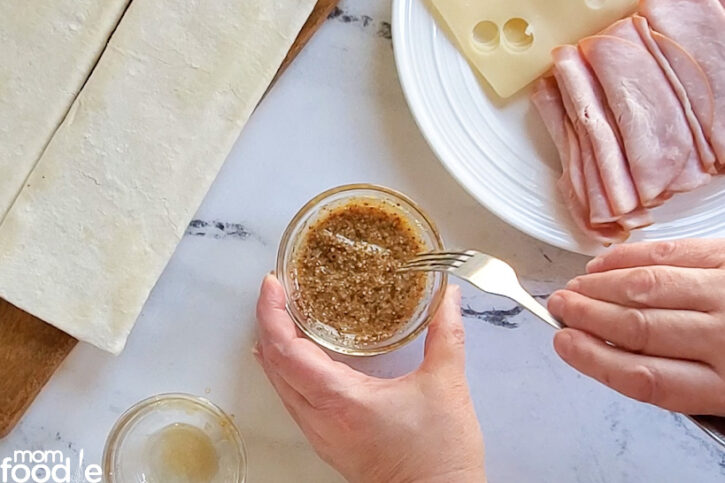 Mixing together the honey, garlic and mustard together in a small dish with a fork.