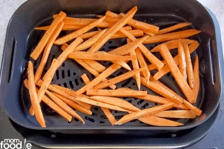 raw sweet potato fries in air fryer basket  in single layer