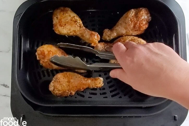 turning the drumsticks with tongs halfway through cooking