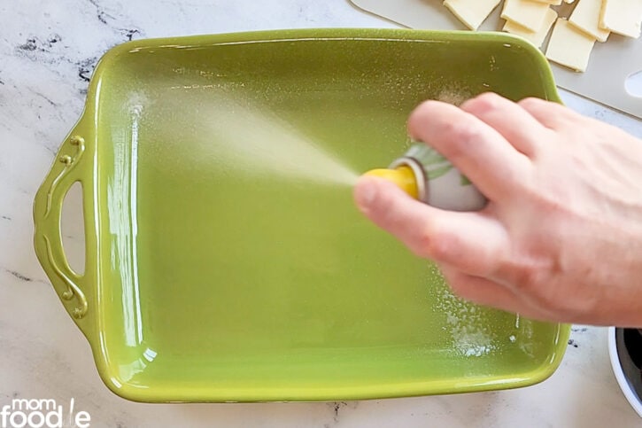 Coating inside of baking pan with cooking spray.