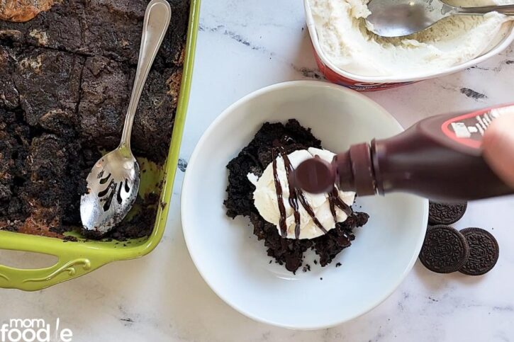 adding ice cream and chocolate syrup on Oreo dump cake