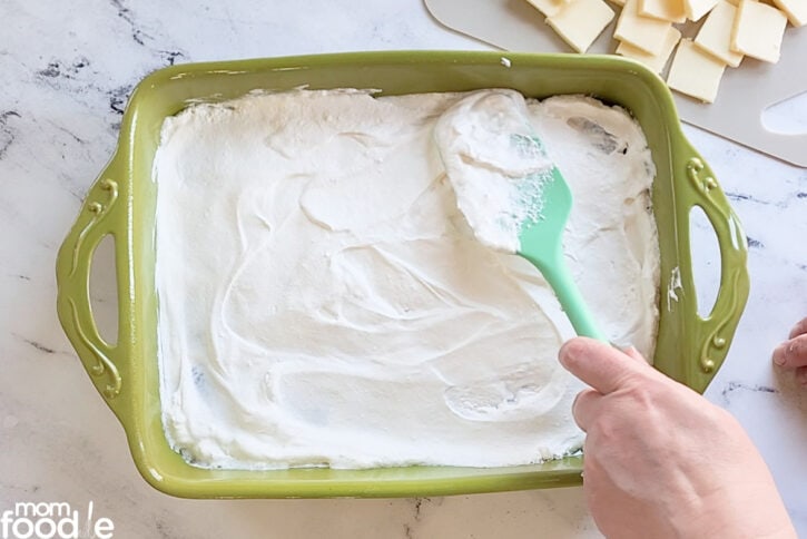 spreading whipped topping over the condensed milk