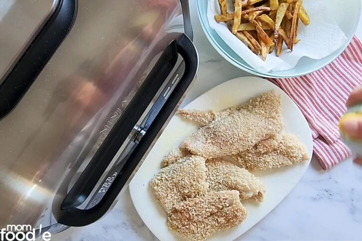 spraying breaded fish with cooking spray