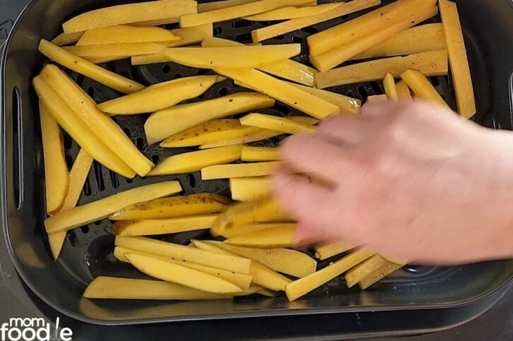 raw fries in air fryer basket in single layer