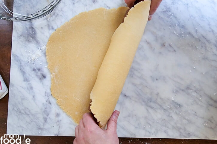 Rolling dough onto rolling pin to transfer to pie plate.