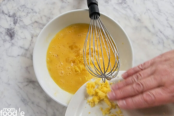 adding lemon zest to beaten eggs 