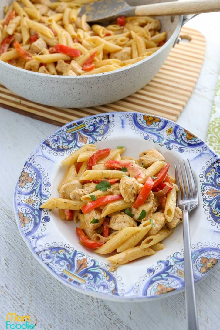 Chicken fajita pasta recipe served in bowl in from of large pot of the meal.