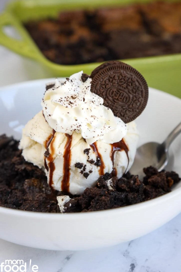 Oreo Dump cake with ice cream, chocolate syrup, whipped cream, crushed Oreo's and a whole cookie on top.