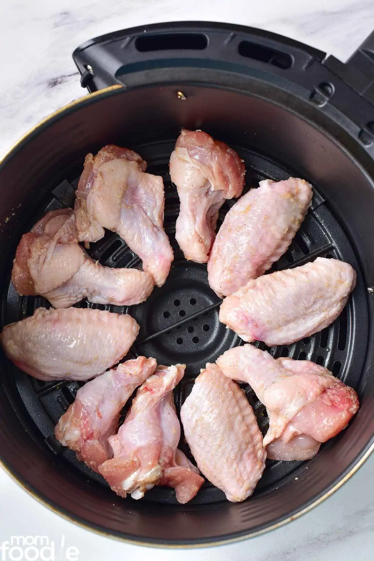 raw chicken wings in air fryer basket.