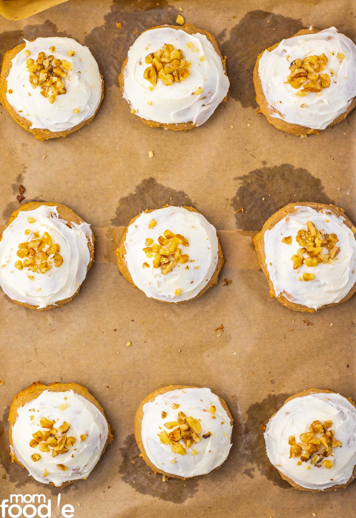applying cream cheese frosting to the carrot cake mix cookies and topping with chopped walnuts