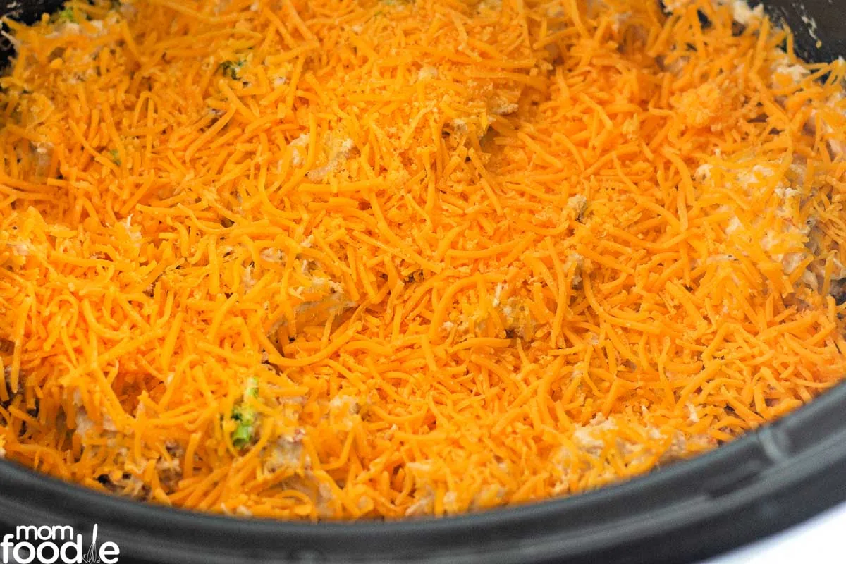 crockpot crack chicken topped with shredded cheddar cheese bacon and green onion.