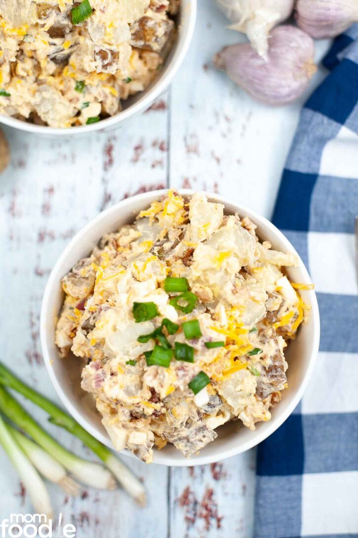 Bowl of loaded baked potato salad with chives on top.