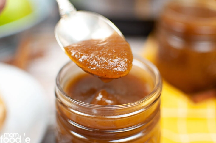 Scooping out apple butter with a spoon.