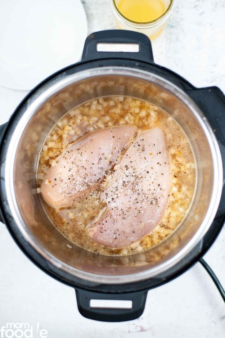 boneless chicken breasts in the pressure cooker with seasonings, onions and broth.