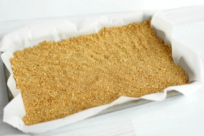 graham cracker crust in parchment paper lined baking pan.