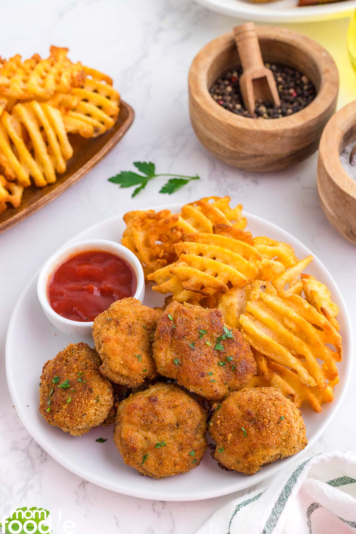 baked breaded nuggets with ground chicken on a plate with waffle fries and ketchup