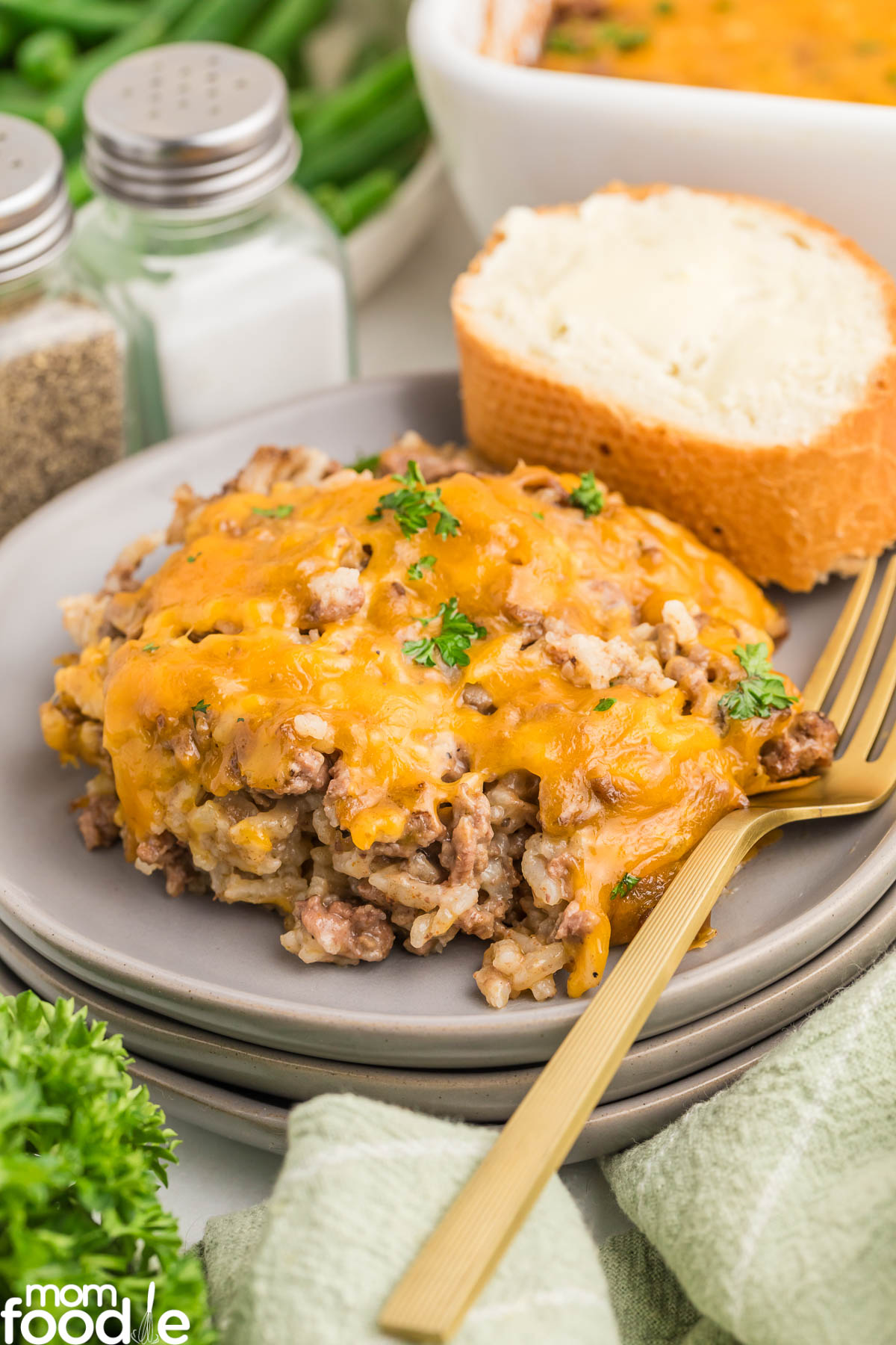 Cheesy Hamburger Rice Casserole recipe prepared and served on gray plate with parsley and bread