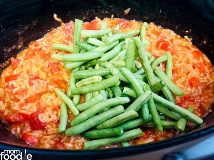 Adding green beans to the slow cooker.
