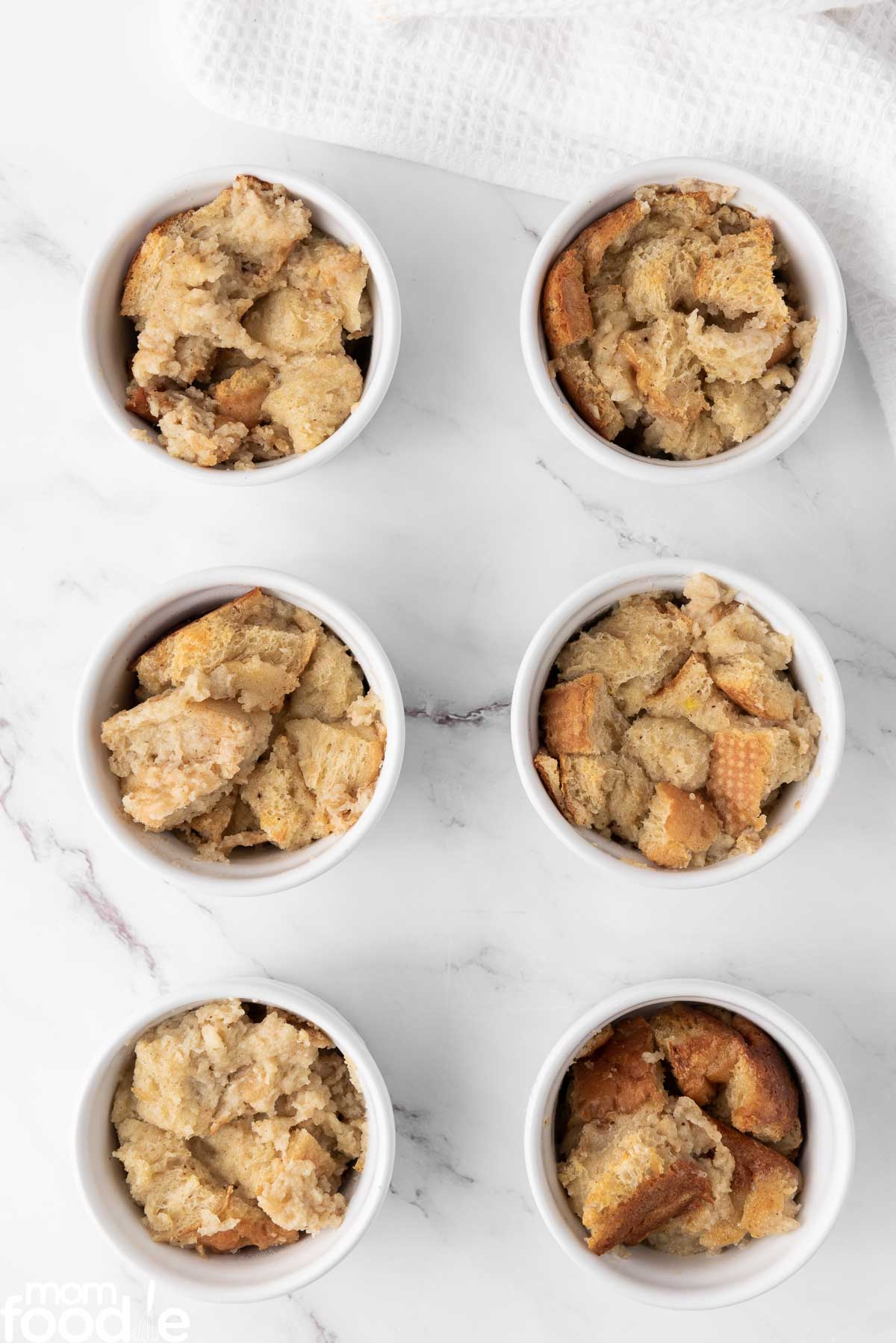 dividing the eggnog bread pudding into ramekin dishes
