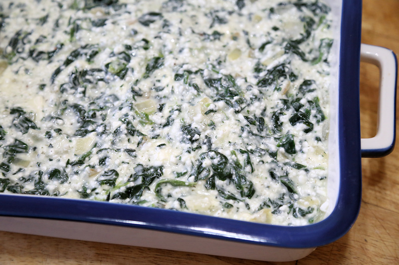 Low carb spanokopita filling spread out in casserole dish before baking