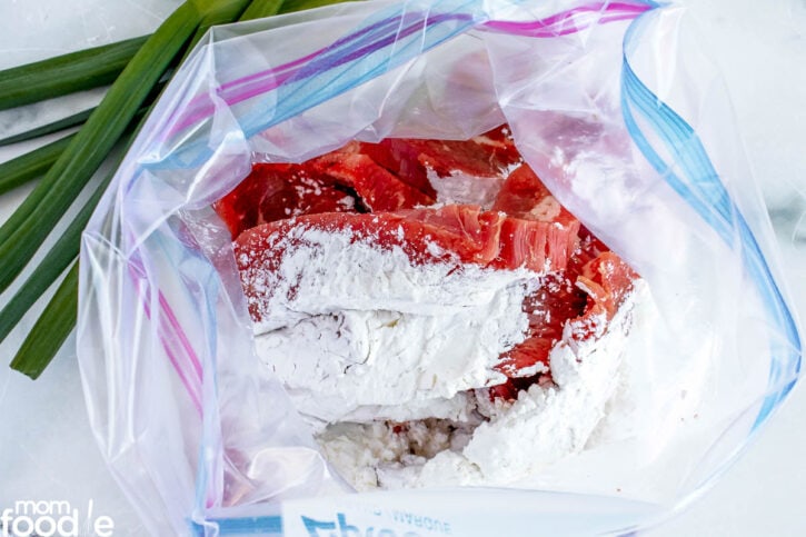 beef  slices and cornstarch in plastic bag ready to be shaken together.
