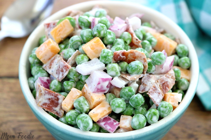 old fashioned pea salad in dressing with cheddar cheese, diced red onions and bacon bits