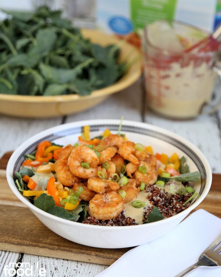 Shrimp and Quinoa Bowl in front of kale salad and hummus dressing