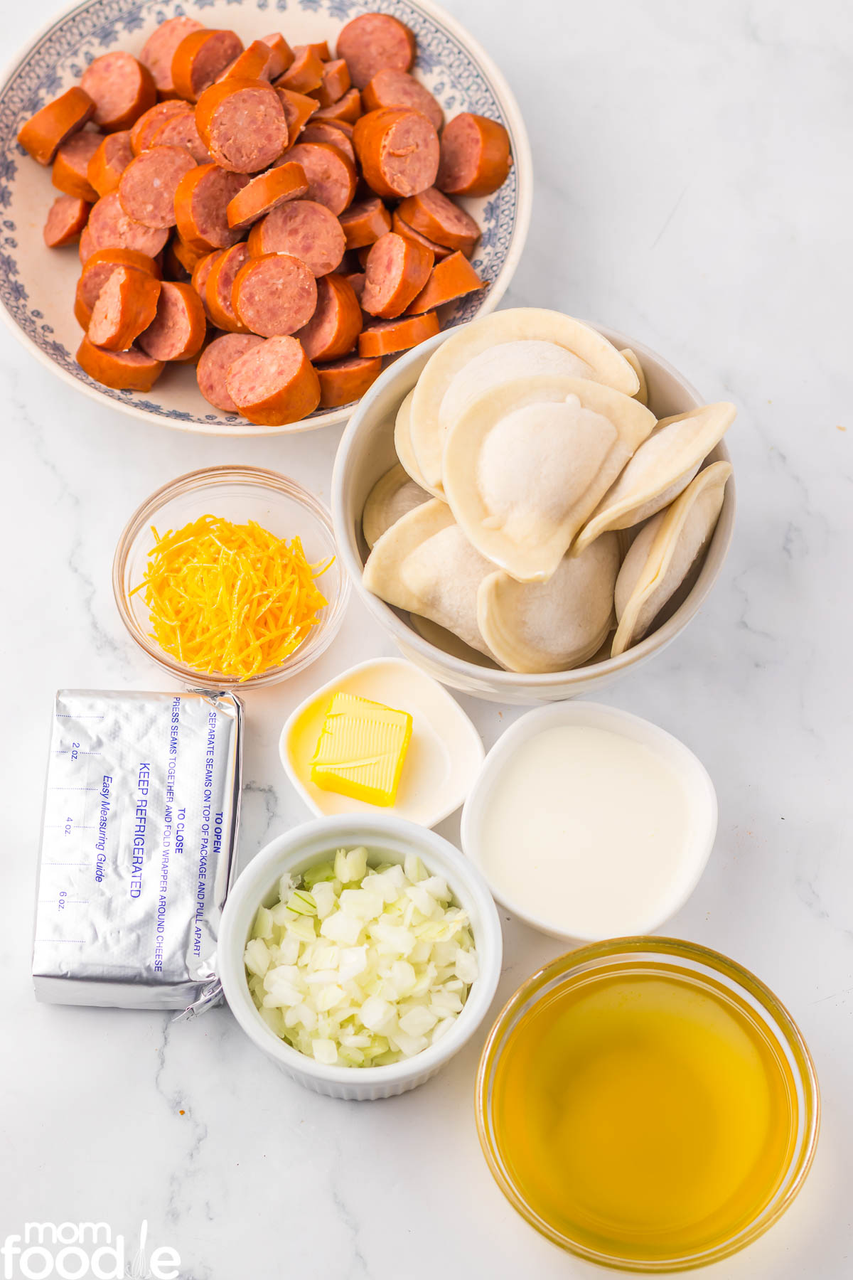 kielbasa, pierogi, shredded cheese, cream cheese, onions, butter, cream and chicken broth for making pierogi casserole