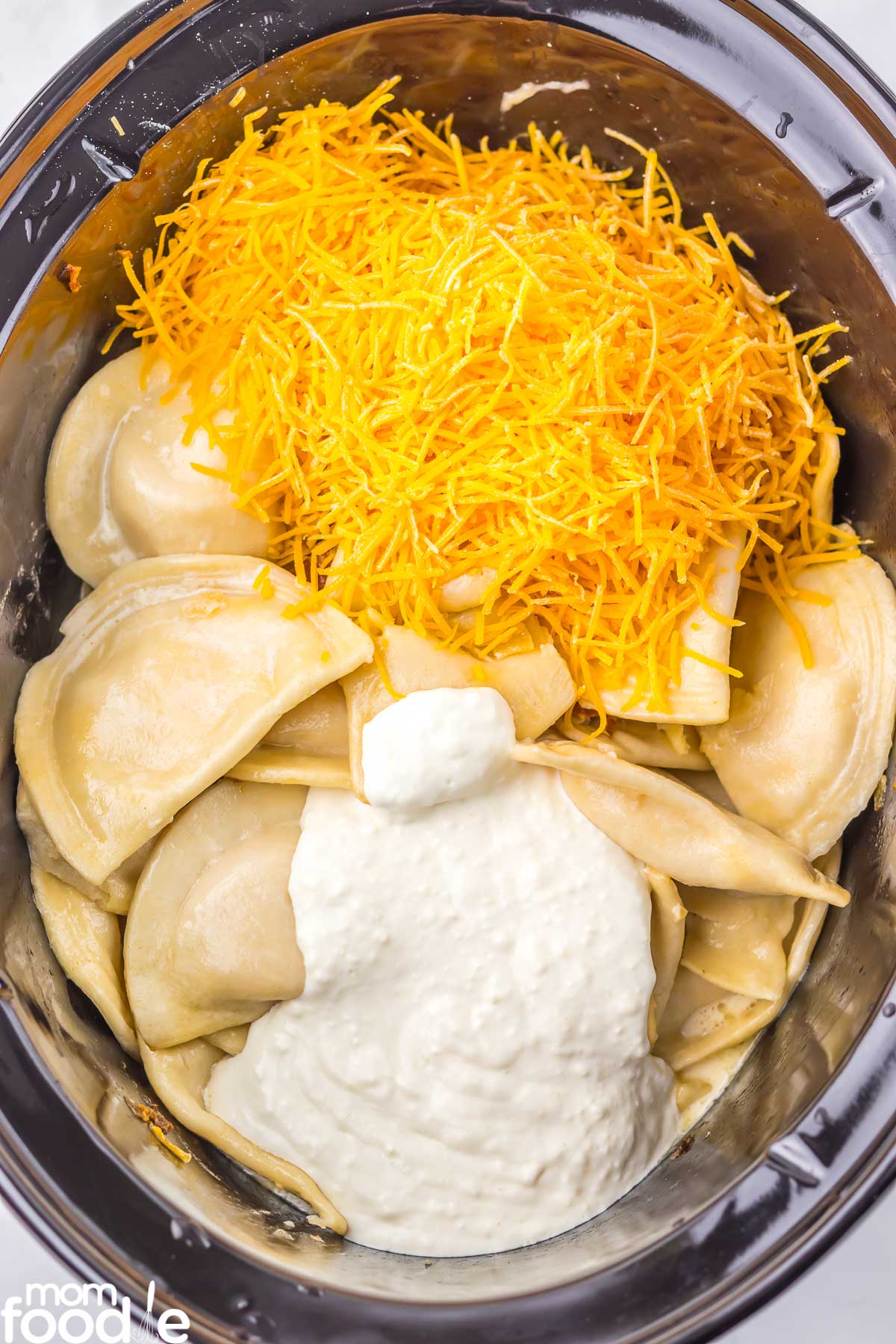 cream cheese mixture and cheddar over the pierogies