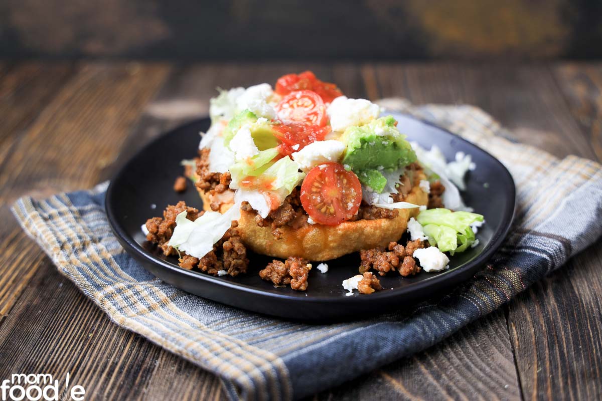 top the sopes with beans, beef, lettuce, tomato and cheese.