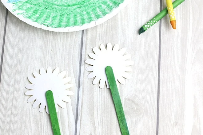 glueing green popsicle sticks on back of paper flowers.