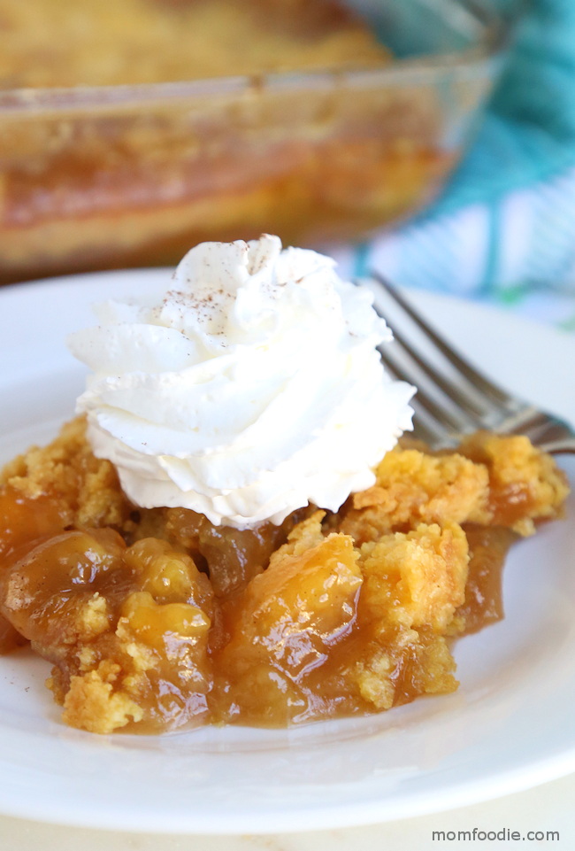 apple dump cake with caramel and whipped cream served on white plate.