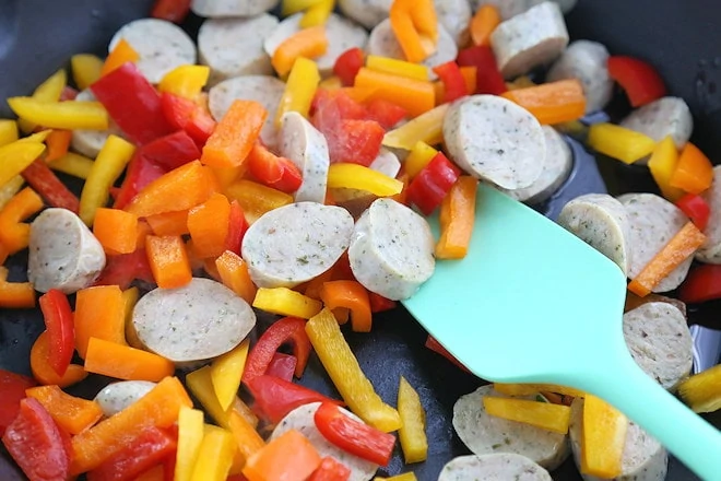 Italian chicken sausage and peppers in skillet frying.