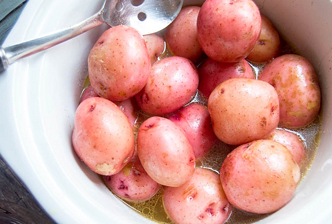 red potatoes in a crockpot with chicken broth.