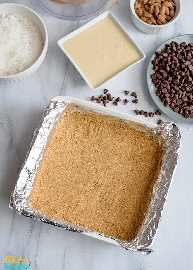 graham base for cookie bars in foil lined pan ready to bake.