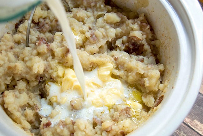 Adding milk and butter to mashed potatoes in the slow cooker.