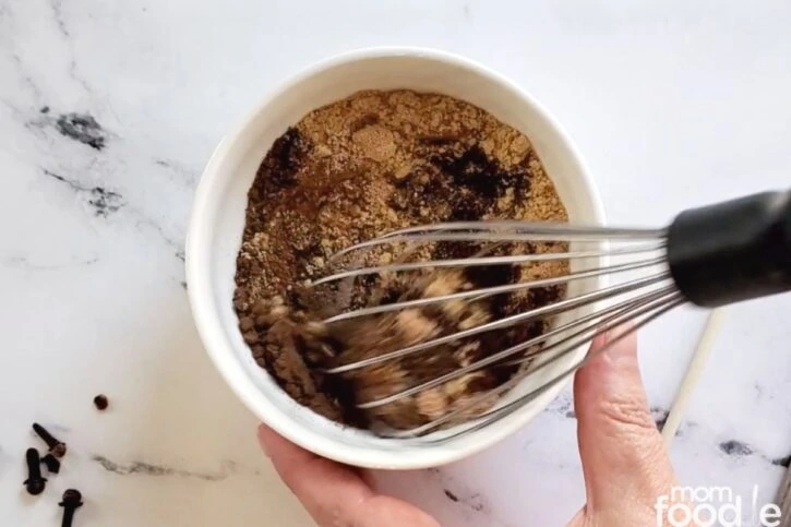 mixing ground spices together with a whisk. cinnamon nutmeg ginger allspice cloves