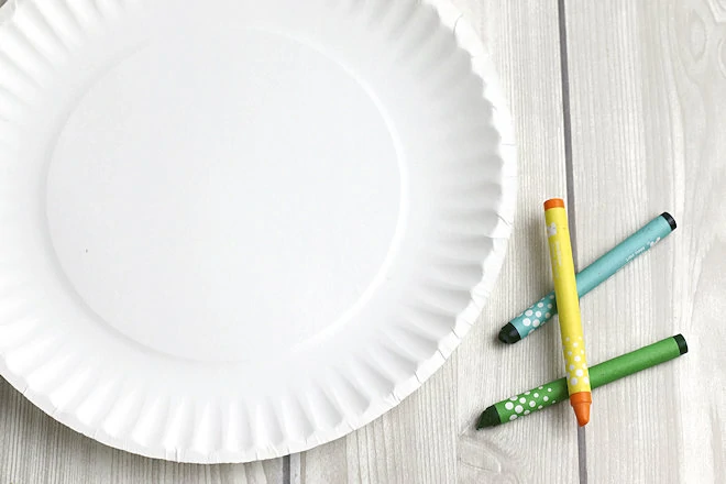 paper plate and crayons on table.