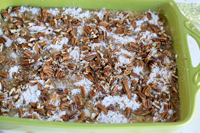 pecans and butter on top of pumpkin pie dump cake ready for oven