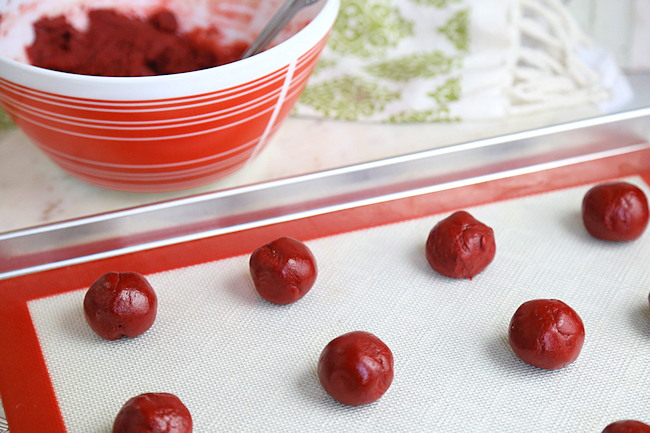 red velvet cookies rolled into balls and placed on cookie sheet with liner, the unbaked cookie dough balls will spread while baking, so they are spread out