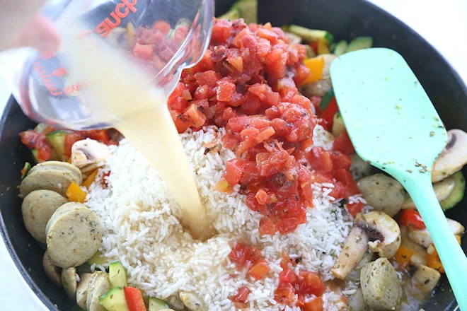 rice tomatoes and broth being added to the chicken sausage dinner.