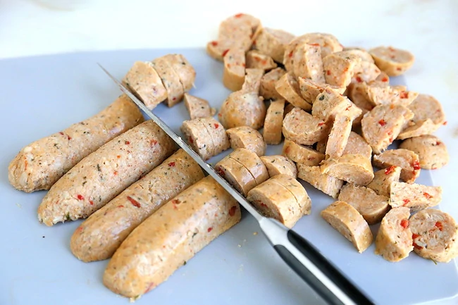 slicing sausage on cutting board.