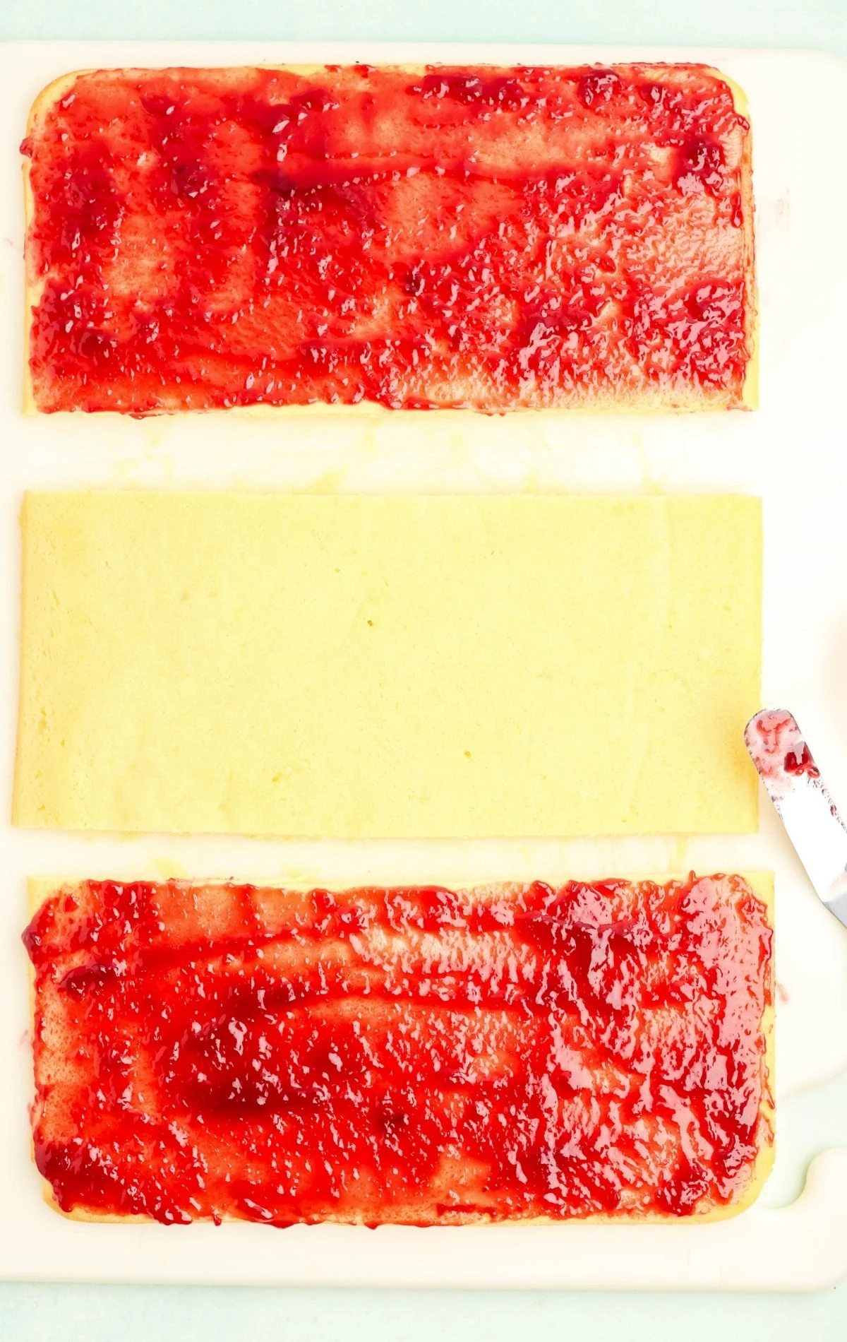 spreading jam on two sections of cake