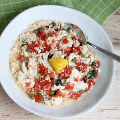 keto chicken foil packets with cauliflower rice, tomato, capers and lemon in serving dish